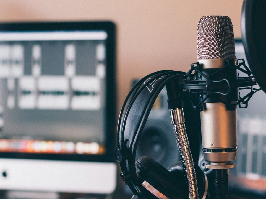 A microphone and headphones in front of an audio edit on screen